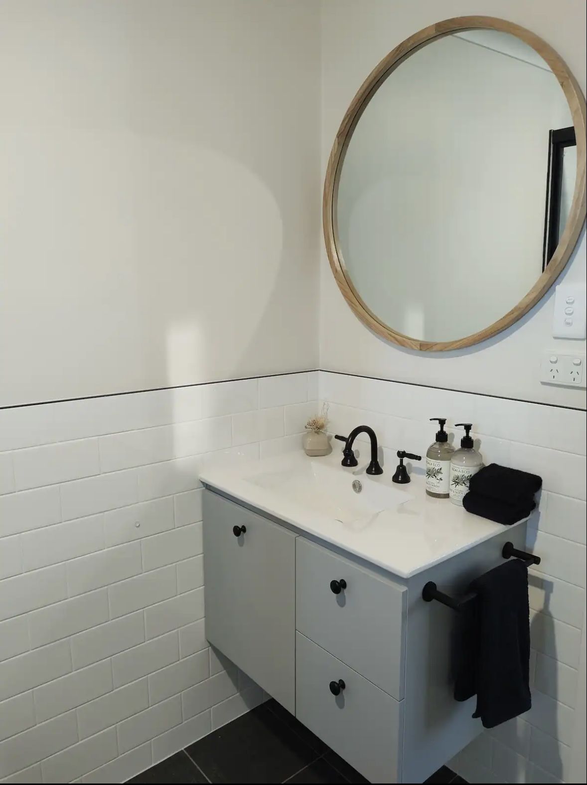 Bathroom with vanity, round mirror and walk-in shower in the self-contained farm cottage