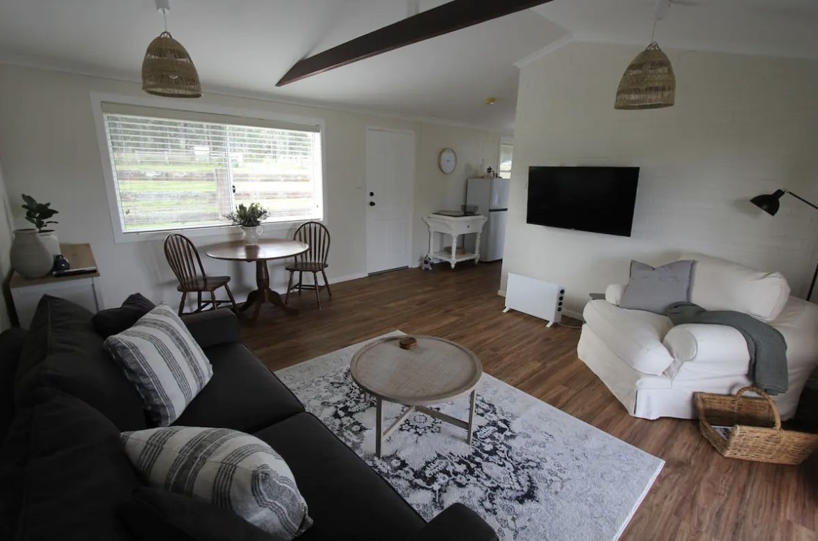 Open living area of the Nabiac farm stay cottage with sofas, dining table and TV