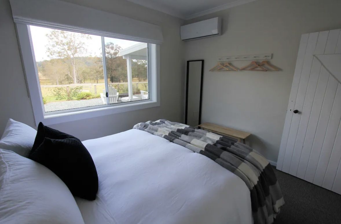 Queen bedroom in the farm cottage with linen turned down and a window over the paddocks